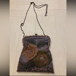 Vintage-style silk handbag with floral appliqués and a delicate chain strap.